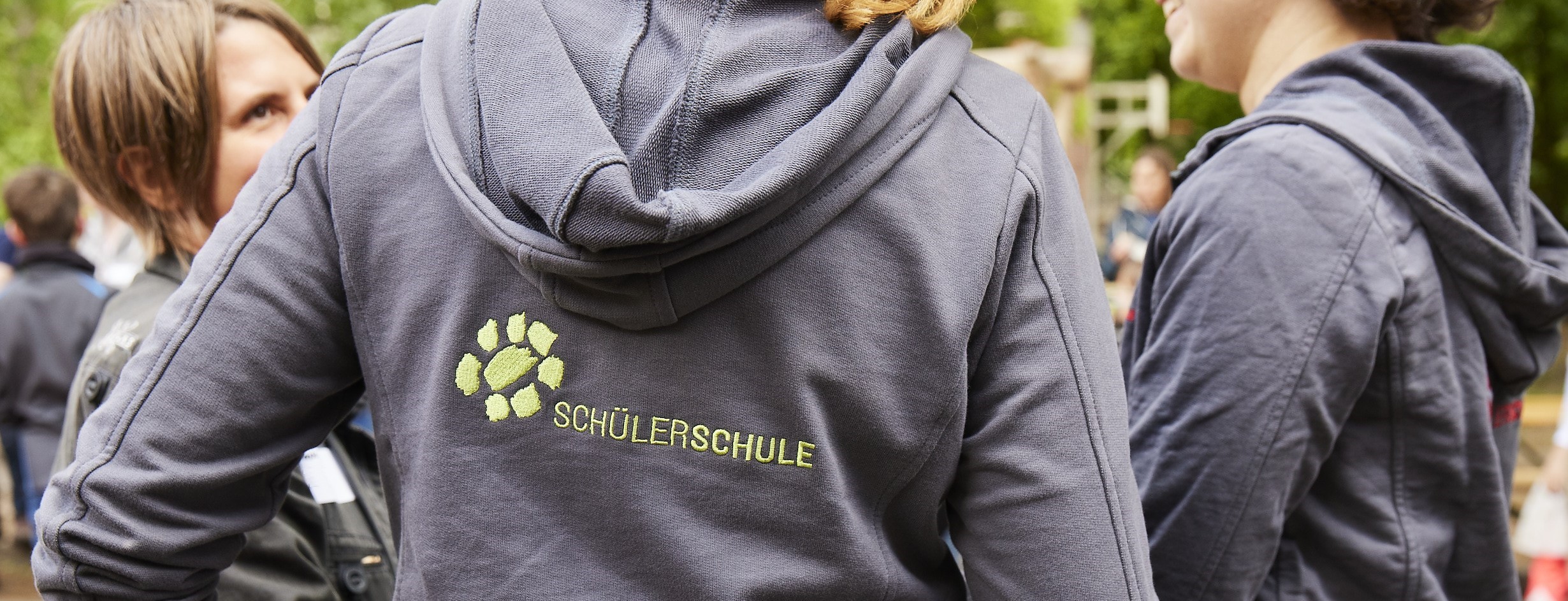 Eltern, die sich unterhalten und Pulli mit Logo tragen